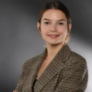 Freundlich aussehende Frau vor neutralem Hintergrund.