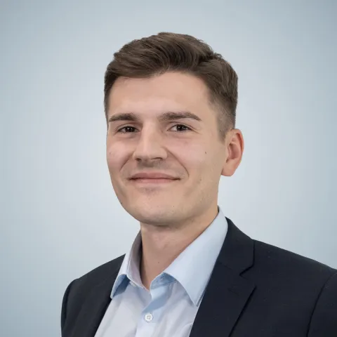 Marvin Gornik Mann, Mitte bis Ende 20, hellblaues Hemd, schwarzes Jackett, kurze braune Haare, braune Augen, sympathisch lächelnd